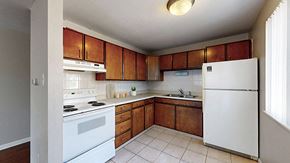 Denver apartment for rent - A kitchen with white appliances and wooden cabinets.