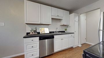 Westminster apartment for rent - A kitchen with white cabinets and a black countertop.