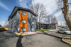 Westminster apartment for rent - A modern building with a grey and orange facade is surrounded by a parking lot.