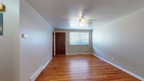 Wheat Ridge apartment for rent - A room with wooden floors and a ceiling fan.