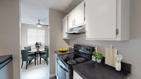 Lakewood apartment for rent - A kitchen with a black countertop and a dining table with chairs.