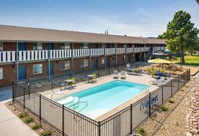 Lakewood apartment for rent - A black fence surrounds a small pool in front of a brick building.