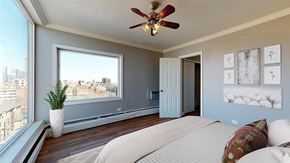 Denver apartment for rent - A bedroom with a large bed and a view of the city.