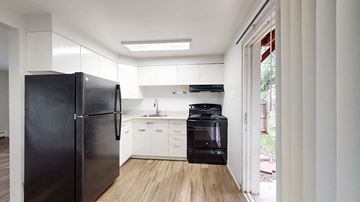 Lakewood apartment for rent - A black refrigerator is in a kitchen with white cabinets.
