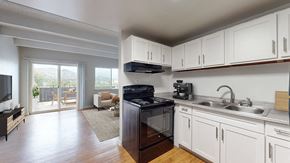Golden apartment for rent - A kitchen with white cabinets and a black stove top oven.
