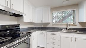 Wheat Ridge apartment for rent - A modern kitchen with white cabinets and a stainless steel stove top.