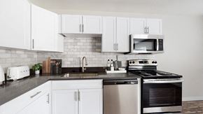Arvada apartment for rent - A modern kitchen with white cabinets and stainless steel appliances.