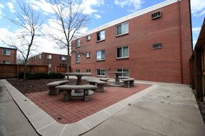 Denver apartment for rent - A red brick building with a concrete patio and tables.