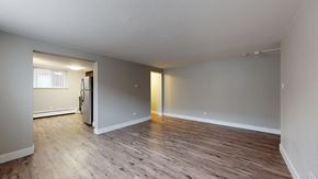 Denver apartment for rent - A spacious room with wooden flooring and white walls.