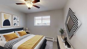 Lakewood apartment for rent - A bedroom with a bed, a mirror, and a ceiling fan.