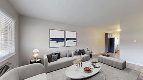 Lakewood apartment for rent - A modern living room with a grey couch, a white coffee table, and a painting on the wall.