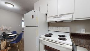 Denver apartment for rent - A white stove and refrigerator in a kitchen with a table and chairs.