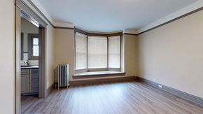 Denver apartment for rent - A room with wooden floors and a window with blinds.