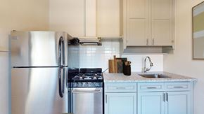 Denver apartment for rent - A kitchen with a stainless steel refrigerator and a stove top oven.
