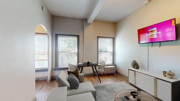 Denver apartment for rent - A living room with a grey sofa and a television on the wall.