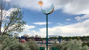Littleton apartment for rent - A playground with a blue swing set and a yellow leaf-shaped object on a pole.