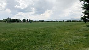 Littleton apartment for rent - A large, open grassy field with a few scattered trees and a cloudy sky overhead.