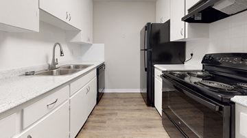 Littleton apartment for rent - A modern kitchen with white cabinets and black appliances.
