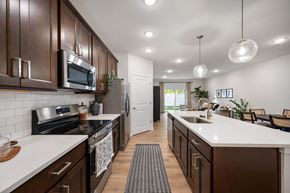 Stow townhouse for rent - A modern kitchen with dark brown cabinets and white countertops.