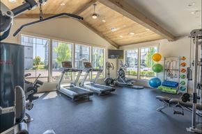 Albany apartment for rent - A spacious gym with a variety of exercise equipment and a large window overlooking the outdoors at Timberridge Place Apartment Homes, Albany, OR, 97322