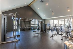 Pendleton apartment for rent - A spacious gym with a variety of equipment including a squat rack, bench, and weights at Westgate Apartment Homes, Pendleton, OR, 97801