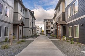 Woodburn apartment for rent - A long concrete walkway leads between two rows of modern townhouses at Woodburn Place Apartment Homes, Woodburn