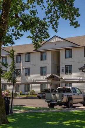 Independence apartment for rent - A large white building with a brown roof and a truck parked in front at Riverplace Apartment Homes, Independence, OR