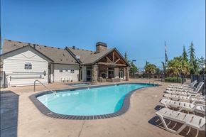 Molalla apartment for rent - A pool with chairs around it and a building in the background at Stoneplace Apartment Homes, Molalla, OR, 97038