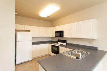 West Lafayette apartment for rent - A kitchen with white cabinets and a black stove top oven.