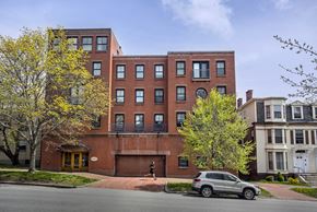 Portland apartment for rent - A grey car is parked in front of a red brick building.