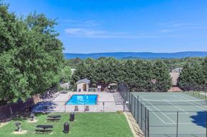 Hixson apartment for rent - A tennis court is surrounded by a fence and a pool is in the background.