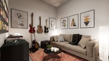A living room with a couch, a coffee table, and a wall with framed pictures and guitars