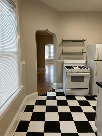 St. Paul apartment for rent - A black and white checkered floor leads to a kitchen with a white stove and refrigerator.