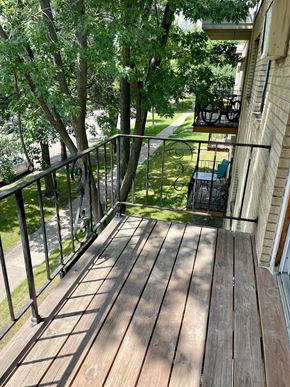 St. Paul apartment for rent - A wooden deck with a metal railing and a tree in the background.