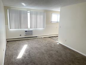Fridley apartment for rent - A room with a window covered by blinds and a small air conditioning unit on the wall.