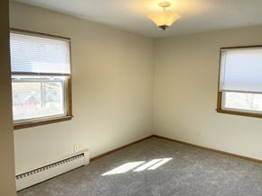 Fridley apartment for rent - A room with a carpeted floor, a window with blinds, and a ceiling fan.
