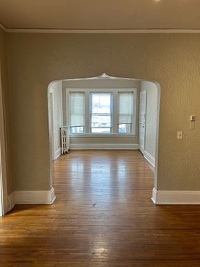 St. Paul apartment for rent - A room with a wooden floor and a white archway leading to a window.