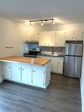 Minneapolis apartment for rent - A kitchen with white cabinets and a wooden island.