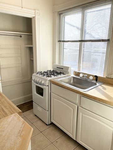 St. Paul apartment for rent - A white kitchen with a stove, sink, and cabinets.