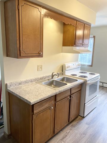 Fridley apartment for rent - A kitchen with a white stove and wooden cabinets.