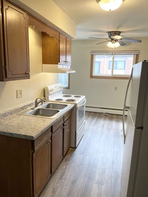 Fridley apartment for rent - A kitchen with wooden cabinets and a white stove top oven.