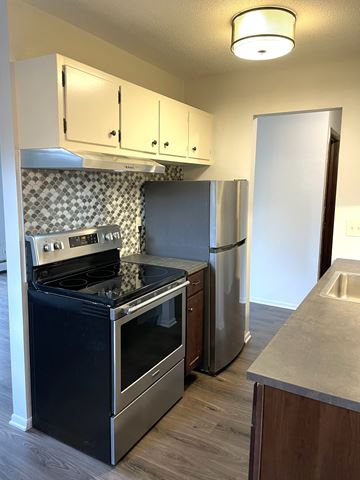 Minneapolis apartment for rent - A kitchen with a black stove top oven and a stainless steel refrigerator.