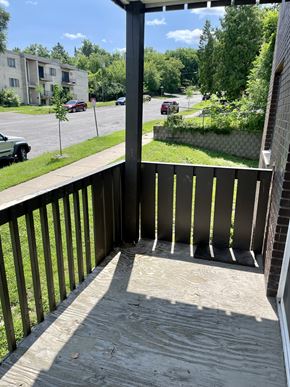 St. Paul apartment for rent - A balcony with a wooden floor and a black railing overlooks a street with cars and buildings.