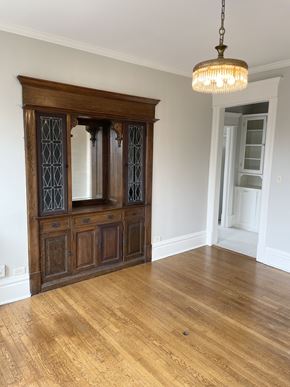 St. Paul apartment for rent - A wooden cabinet with glass doors is in the middle of a room with a chandelier hanging from the ceiling.