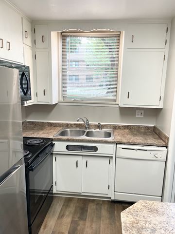 St. Paul apartment for rent - A kitchen with white cabinets and a black stove top oven.