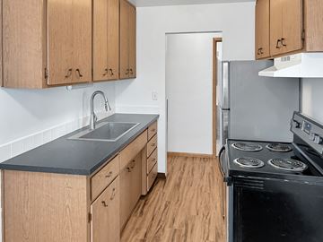 St. Paul apartment for rent - A kitchen with wooden cabinets and a black stove top oven.