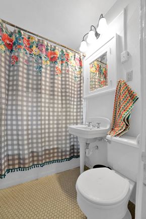 St. Paul apartment for rent - A white toilet sits under a shower curtain with a floral pattern.