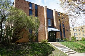 Minneapolis apartment for rent - A red brick building with a black awning and a set of stairs leading up to the entrance.