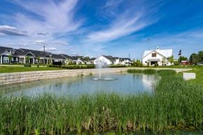 Lewis Center apartment for rent - A white building with a flag on top stands behind a pond with a fountain in the middle.