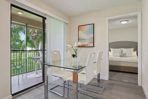 Miami apartment for rent - A dining room with a glass table and chairs and a painting on the wall.